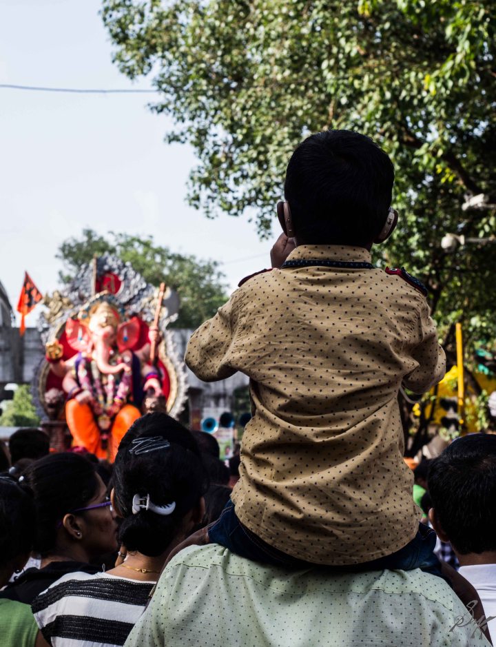 A boy sits on his father's shoulder during the Visarjan A boy sits on his father's shoulder during the Visarjan