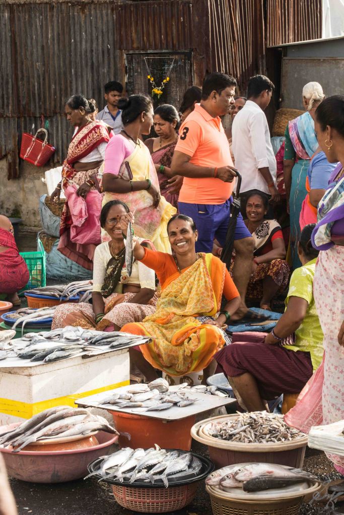 Lady holds up a fish for display, Sassoon Docks, Mumbai, India
