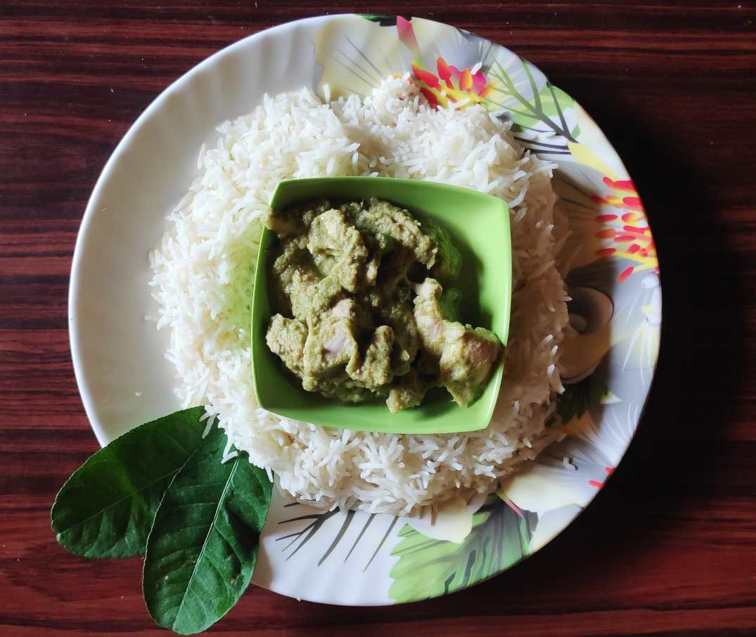 A bowl of chicken thai curry within a bed of white rice.